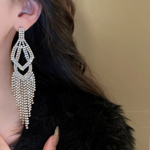 Close-up of model wearing silver tassel rhinestone drop earrings with geometric design