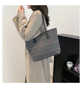 Close-up of a large houndstooth tote bag featuring red accents and black shoulder straps