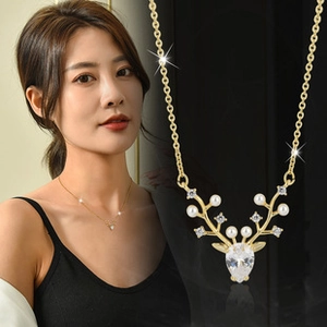 Detail of golden reindeer antler necklace with white pearl and crystal stones