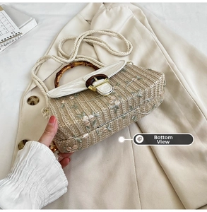 Detailed bottom view of straw woven bag with floral embroidery and bamboo handle