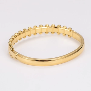 Detail of gold-plated stainless steel bangle with wave pattern and cubic zirconia stones
