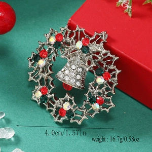 Detailed Christmas wreath brooch with sparkling rhinestones and bells on a green background