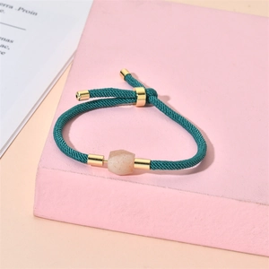 Detail of adjustable green woven cord bracelet with pink stone and gold accents