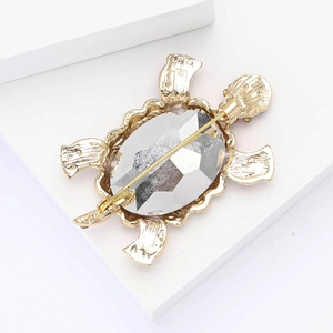 Macro view of gold turtle brooch back showing faceted crystal and safety pin clasp