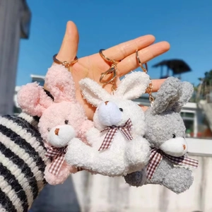 Trois porte-clés lapins en peluche rose, blanc et gris avec nœuds papillon à carreaux