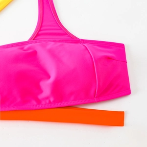 Dettaglio del top bikini monospalla color-block rosa e arancione ad alta elasticità