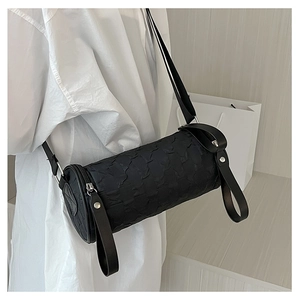 Detail of black cylindrical crossbody bag with pleated texture and wide shoulder strap