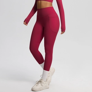 Detail of red high-waisted yoga leggings with side pockets and seamless stitching