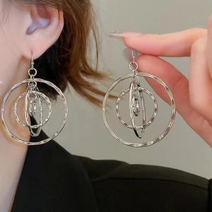 Macro view of silver layered hollow geometric hoop earrings with metallic texture