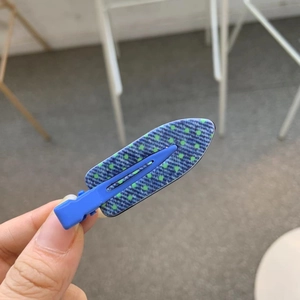 Close-up of blue denim texture hair clip with green polka dots and metal duckbill clip