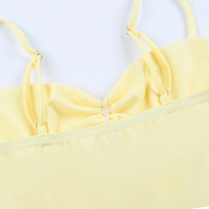 Detail of adjustable thin shoulder straps and gathered pleats on yellow mini dress