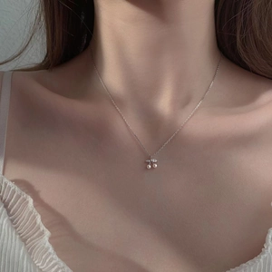 Detail of cute cherry pendant necklace with pearls and zircons on a model's collarbone