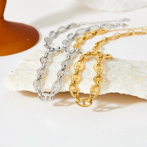 Detail of interlocking link necklaces in gold and silver finish on stone base