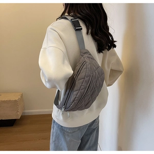 Rear view of model wearing a grey quilted nylon crossbody bag with adjustable strap