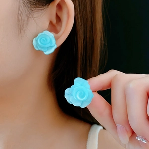 Détail macro de boucles d'oreilles roses en résine bleu ciel avec vue sur le porté chic