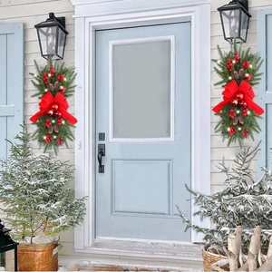 Christmas door swag with red bow, pine cones, and LED lights on a snowy entrance