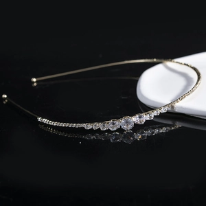 Elegant gold metal headband with sparkling clear rhinestones on reflective black background