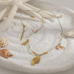 Detail of woven beach necklace with gold fishbone, seahorse charms and sea shells