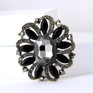 Close-up of vintage flower brooch featuring grey crystals and antique gold metal base
