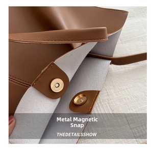 Detail show of golden magnetic snap closure and texture on brown leather tote bag
