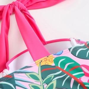 Macro detail of hot pink bow strap and tropical leaf print fabric for women's swimwear
