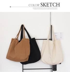 Three minimalist canvas tote bags in brown, black, and beige hanging on a display rack