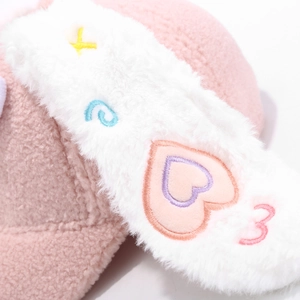 Detailaufnahme von rosa Teddy-Fleece mit bunter Herz-Stickerei auf einer Mütze
