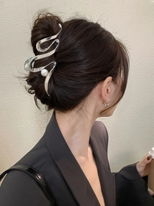 Detail of silver wavy metal hair claw clip with pearl accent on model's hair