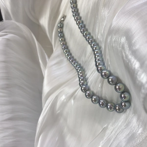 Macro detail of round grey Akoya-style pearls with silver luster on white silk fabric