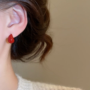 Close-up of elegant red teardrop earrings worn by model for retro style