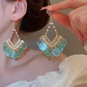 Golden hollow hoop earrings with white pearls and light blue resin fringe tassels
