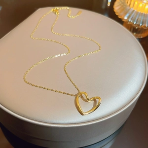 Detailed view of a gold-toned hollow heart pendant necklace on a luxury display box
