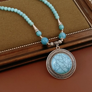 Close-up of vintage bohemian beaded necklace with blue turquoise and carved silver pendant
