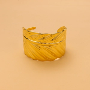 Macro detail of golden leaf-shaped cuff bracelet showing fine metal vein texture