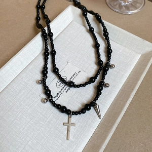 Detail of Y2K black glass beaded necklace with silver cross and spike pendant