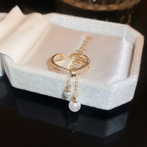 Macro view of double-layered gold ring with zircon stones and hanging pearls detail