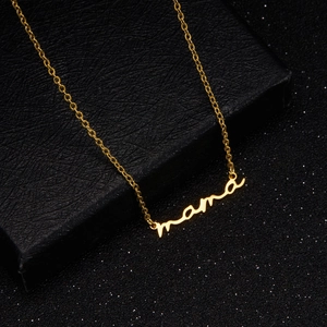 Close-up of golden Mama pendant necklace with artistic script on black jewelry box