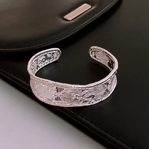 Close-up of vintage silver cuff bracelet with geometric texture on black leather