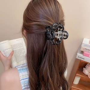 Detail view of a black and white gingham flower claw clip in a stylish half-up hairstyle