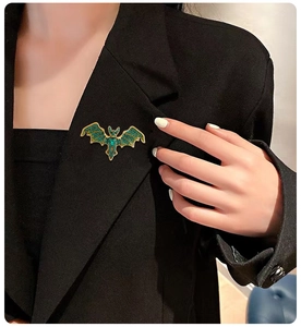 Macro shot of a vintage bat brooch with emerald rhinestones on a black suit lapel