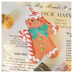 Detailed view of gingerbread man Christmas ornament with green bow on vintage paper