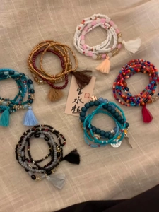 Detail of layered bohemian seed bead bracelets with decorative fringe tassels on fabric