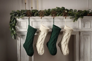 Classic Christmas stockings with cable knit patterns hanging on a decorated fireplace
