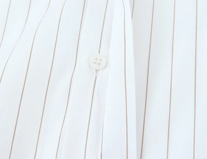 Macro detail of white shirt featuring brown vertical stripes and a classic white button