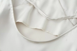 Detail of white satin dress featuring delicate lace trim and fine stitching at the neckline
