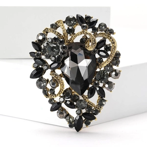 Vintage gold brooch with pear-cut black gemstone and grey rhinestones on a white block