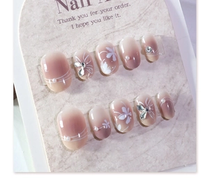 Close-up of pink gradient press-on nails with white flower art and small pearls