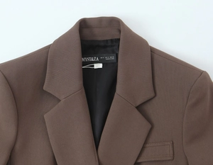 Gros plan du col d'un blazer marron avec étiquette MYST&ZA et texture de tissu sergé