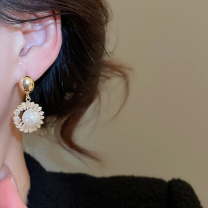 Close-up of 18k gold plated pearl drop earrings with sparkling zircon halo on ear