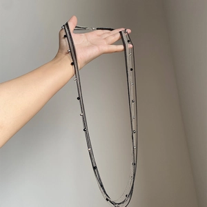 Collana a strati con catene argentate e perle nere in stile minimalista e design dark
